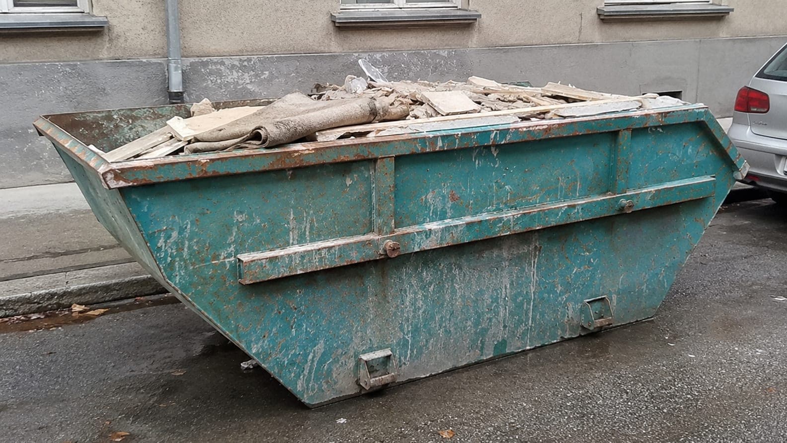 Konténer egy felújítás alatt álló angyalföldi társasház előtt, építési törmelékkel — sittszállítás a XIII. kerületben